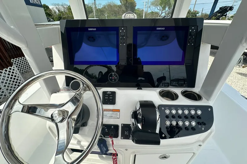 Slide: The Image of 2024 NauticStar 274 Bay boat dashboard with dual Simrad displays and steering wheel. - 8