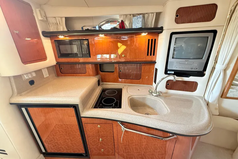 Slide: The Image of 2001 Sea Ray 340 Sundancer galley with wood cabinetry, sink, stove, microwave, and TV. - 18