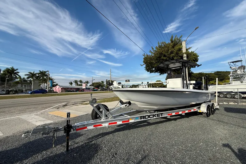 Slide: The Image of 2021 Contender 25 Bay boat on Rocket trailer, parked roadside under clear blue sky. - 3