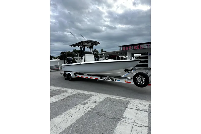 Slide: The Image of 2021 Contender 25 Bay boat with powerful engine, parked near road and trees. - 8