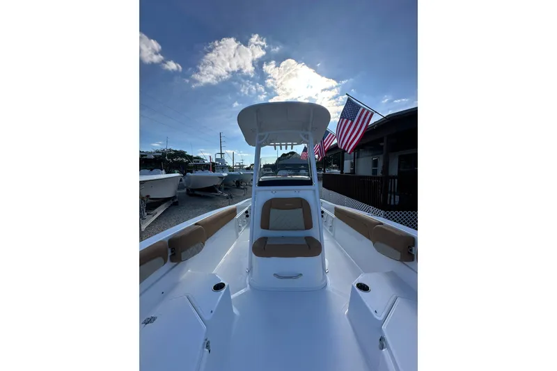 Slide: The Image of 2025 NauticStar 231 Hybrid boat with American flags, under a clear blue sky. - 5