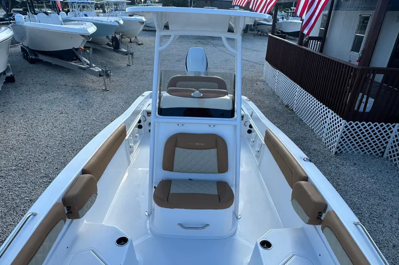 Slide: The Image of 2025 NauticStar 231 Hybrid boat with tan seating, docked in a marina. - 6