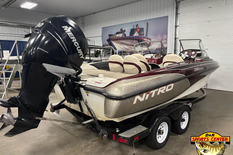 Slide: The Image of 2009 Nitro 290 Sport boat with Mercury engine in showroom, featuring sleek design and trailer. - 2