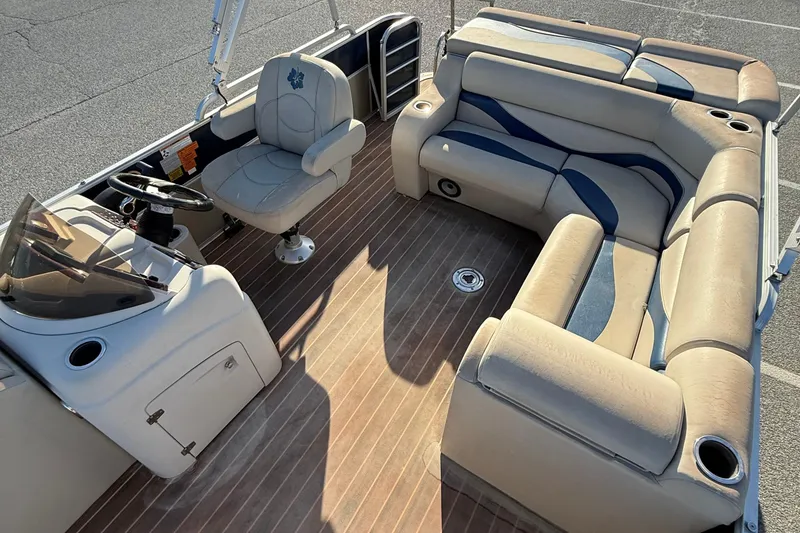 Slide: The Image of 2012 Berkshire 210CL Premium pontoon boat interior with beige seating and wood-style flooring. - 10