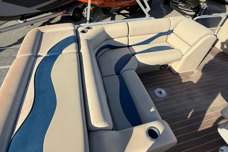 Slide: The Image of 2012 Berkshire 210CL Premium boat interior with beige and blue seating, cup holders, and wood flooring. - 12