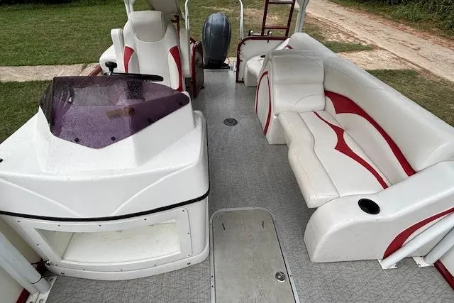 Slide: The Image of 2022 Aloha Pontoon Tropical 260 interior with white and red seating, steering console, and outboard motor. - 11