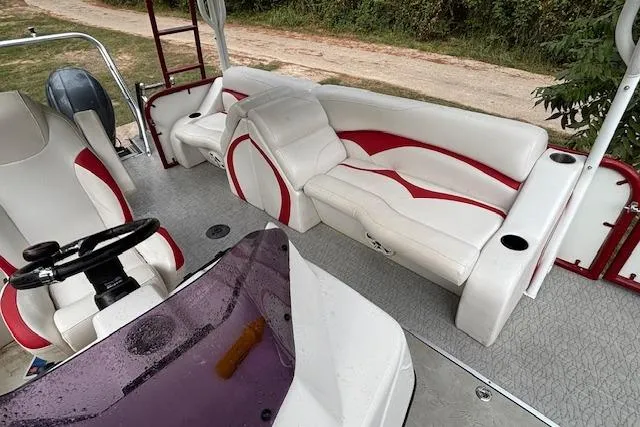 Slide: The Image of 2022 Aloha Pontoon Tropical 260 interior with white and red seating, steering wheel, and console. - 12