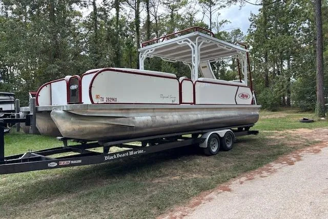 Slide: The Image of 2022 Aloha Pontoon Tropical 260 on trailer, parked in wooded area. - 3