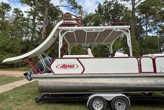Slide: The Image of 2022 Aloha Pontoon Tropical 260 with slide, parked on trailer, surrounded by trees. - 4