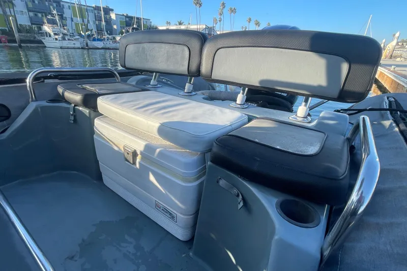 Slide: The Image of 2016 Zodiac Pro Classic 650 boat interior with seating and storage, docked near modern buildings. - 11