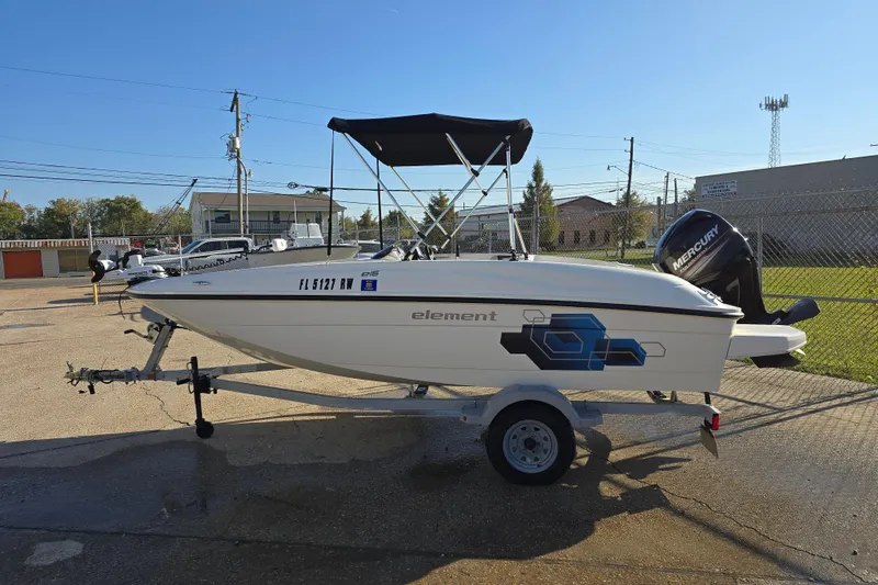 Slide: The Image of 2019 Bayliner Element E16 boat on trailer, parked outdoors under clear sky. - 10