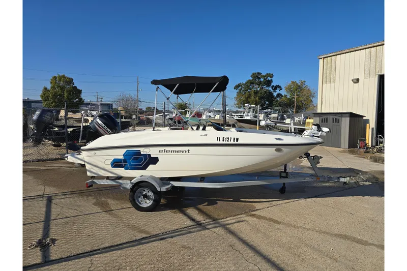 Slide: The Image of 2019 Bayliner Element E16 boat on trailer, parked outdoors under clear blue sky. - 5