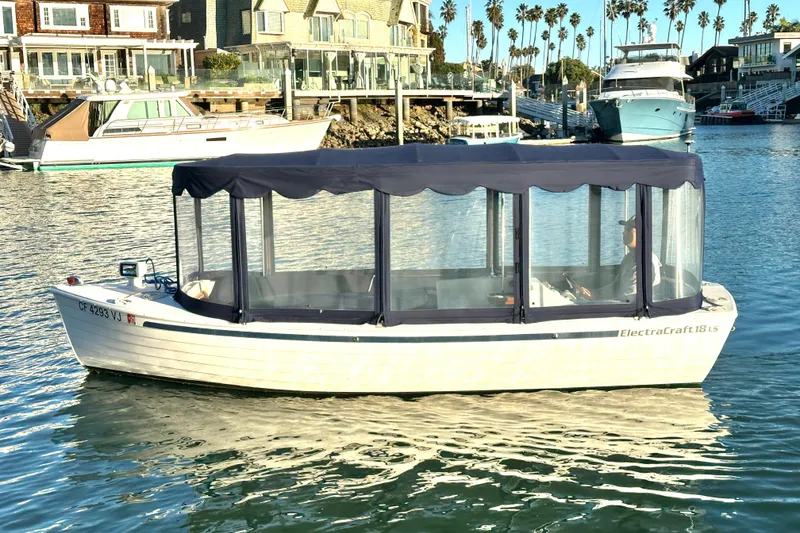 Slide: The Image of 2017 ElectraCraft 18 LS boat on calm water near waterfront homes. - 2