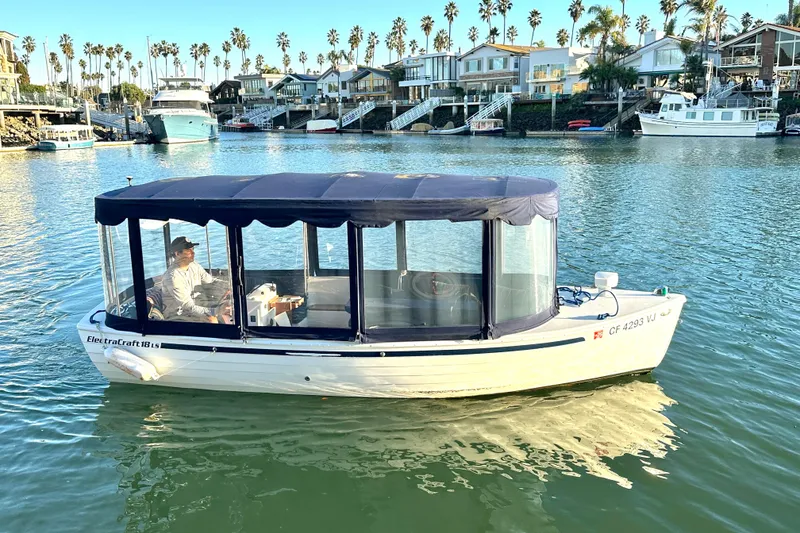 Slide: The Image of 2017 ElectraCraft 18 LS boat cruising in a scenic waterfront area with palm trees. - 3