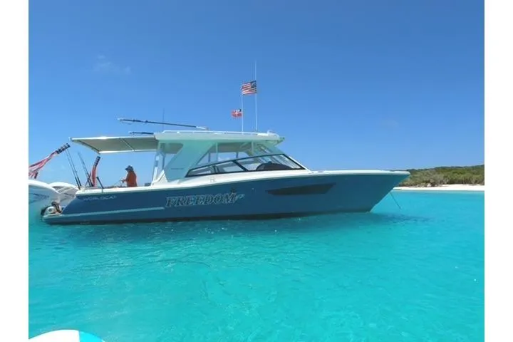 Slide: The Image of 2021 World Cat 400 DC-X boat on clear turquoise water, under a bright blue sky. - 53