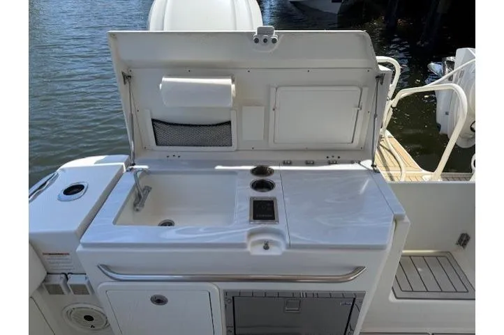 Slide: The Image of 2021 World Cat 400 DC-X boat kitchenette with sink and storage, docked by water. - 56