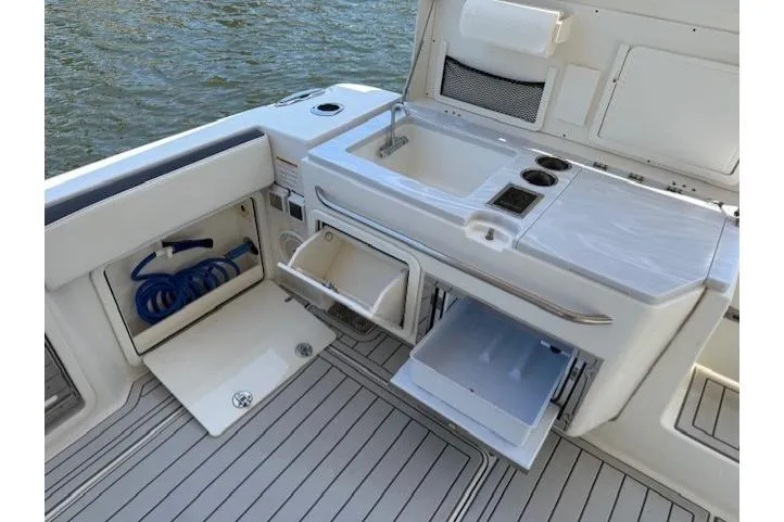 Slide: The Image of World Cat 400 DC-X 2021 boat interior with sink, storage, and water hose. - 64