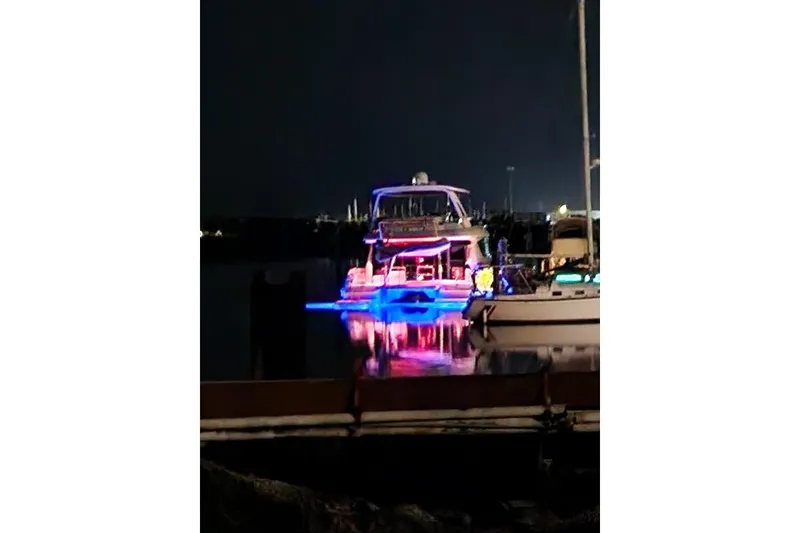 Slide: The Image of Aquila 48 PC 2014 yacht illuminated with vibrant lights at night in a marina. - 27