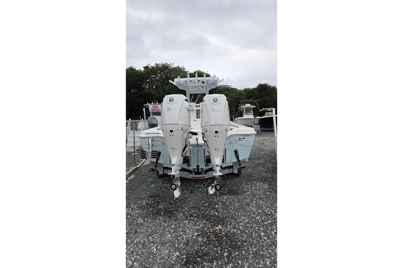 Slide: The Image of 2026 Blazer Bay Makaira 2800 boat with dual outboard motors, parked on gravel. - 16