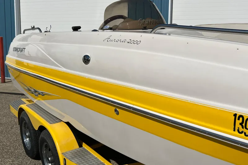 Slide: The Image of 2004 Starcraft Aurora 2000 I/O boat with yellow and white design on trailer. - 9