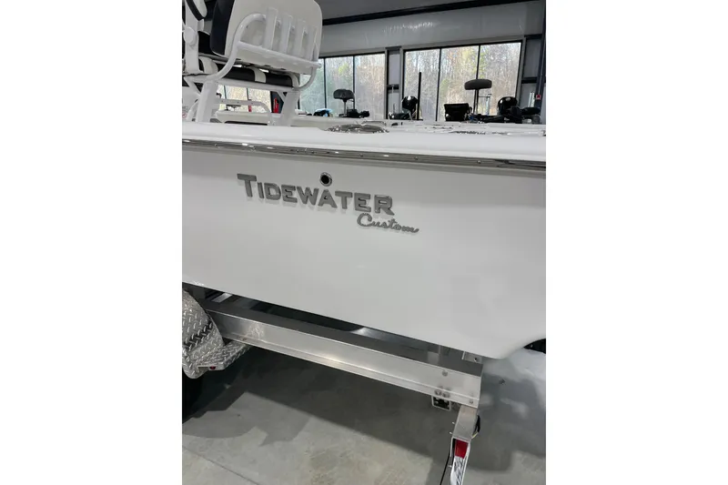 Slide: The Image of 2026 Tidewater 2500 Carolina Bay boat in showroom, featuring sleek white design. - 1