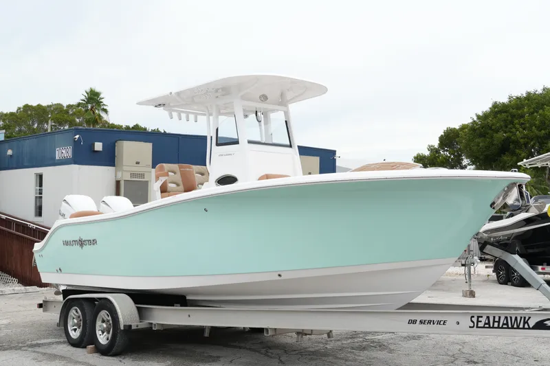 The Image of 2025 NauticStar 252 Legacy boat on trailer, light blue hull, parked outdoors. - 1