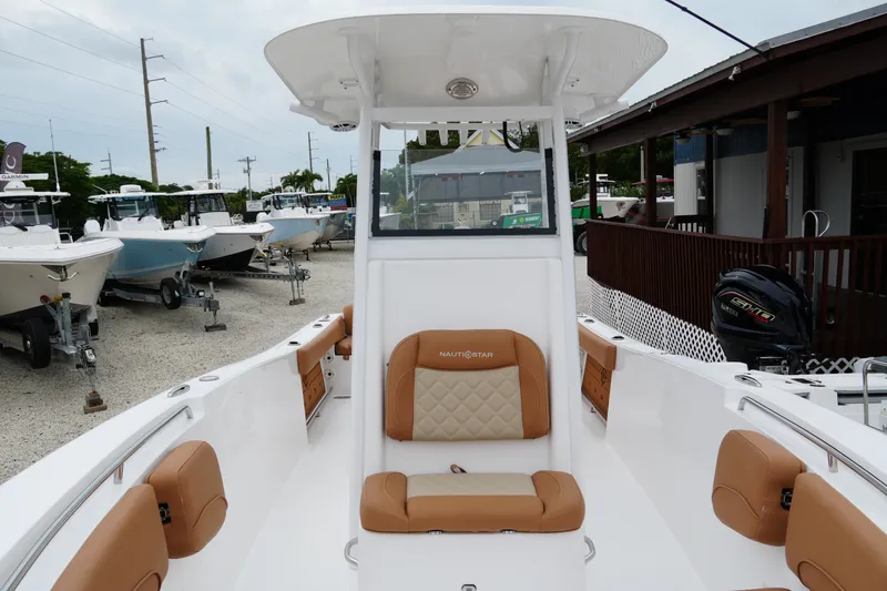 Slide: The Image of 2025 NauticStar 252 Legacy boat interior with tan seating, displayed at a marina. - 14