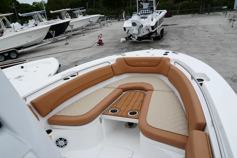Slide: The Image of 2025 NauticStar 252 Legacy boat with tan seating and cup holders in a marina. - 16