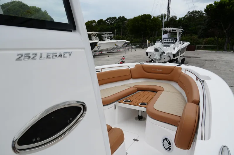 Slide: The Image of 2025 NauticStar 252 Legacy boat with tan seating and sleek design in a marina setting. - 17