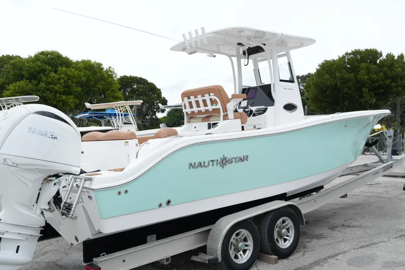 Slide: The Image of 2025 NauticStar 252 Legacy boat on trailer, featuring Yamaha engine, light blue hull. - 2