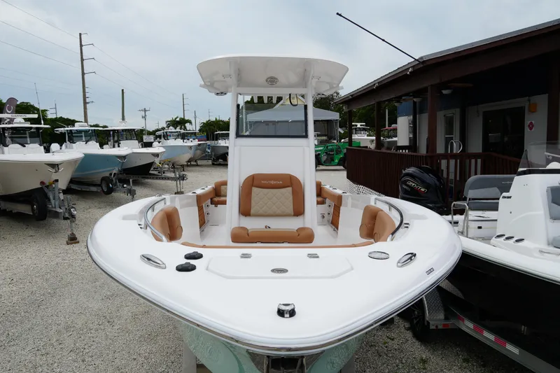 Slide: The Image of 2025 NauticStar 252 Legacy boat with tan seating, displayed outdoors at a dealership. - 9