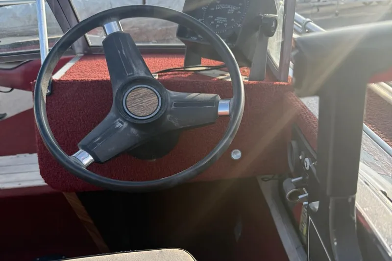 Slide: The Image of 1988 Smoker Craft Magnum 162 boat steering wheel and dashboard, featuring red interior. - 3