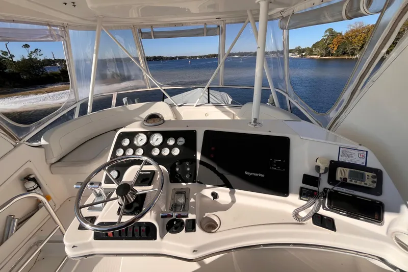 Slide: The Image of Helm of 2001 Silverton 42C yacht with navigational instruments, steering wheel, and scenic water view. - 13