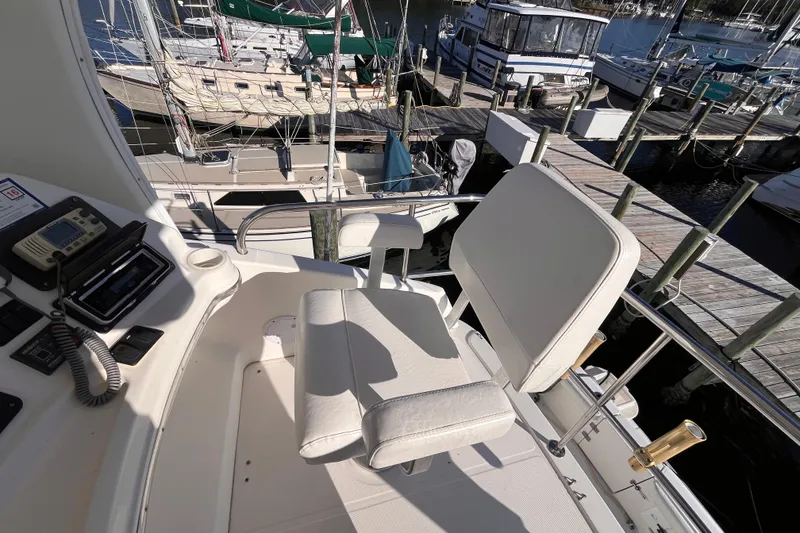 Slide: The Image of 2001 Silverton 42C yacht helm with white captain's chair, docked at marina. - 24
