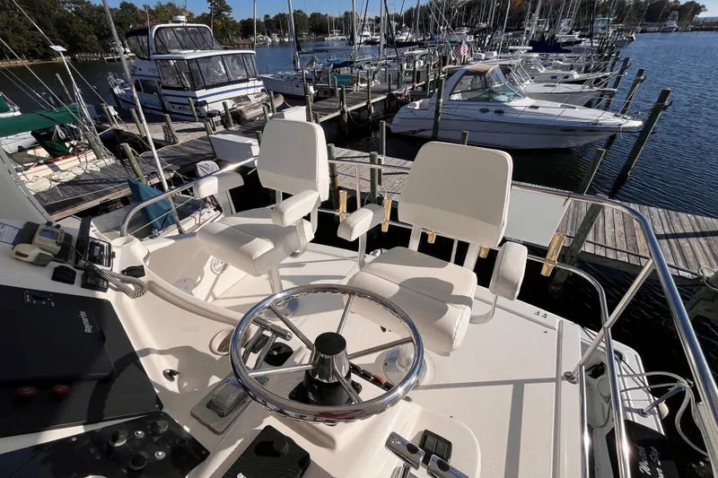Slide: The Image of 2001 Silverton 42C yacht helm with dual white captain chairs at marina. - 25