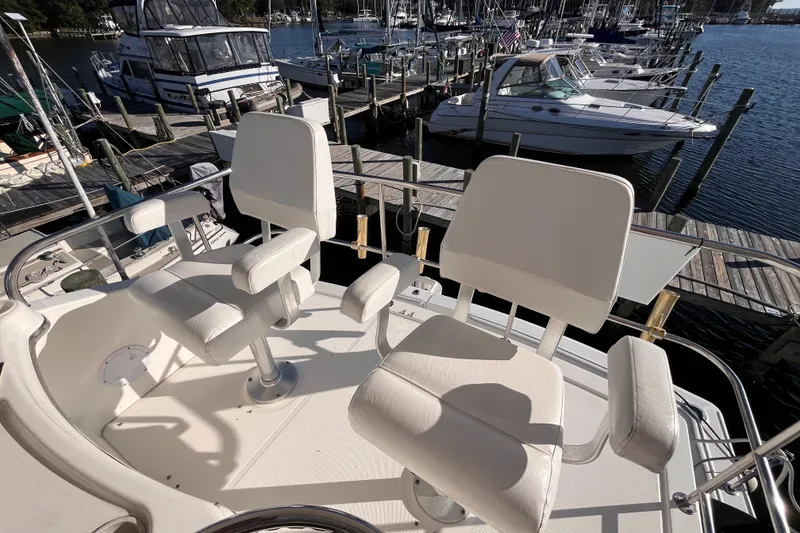 Slide: The Image of Two white captain chairs on a 2001 Silverton 42C yacht at a marina. - 26