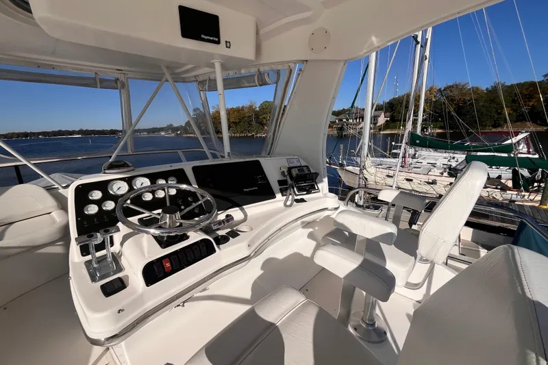 Slide: The Image of 2001 Silverton 42C yacht helm with steering wheel, gauges, and seating, docked by a marina. - 27