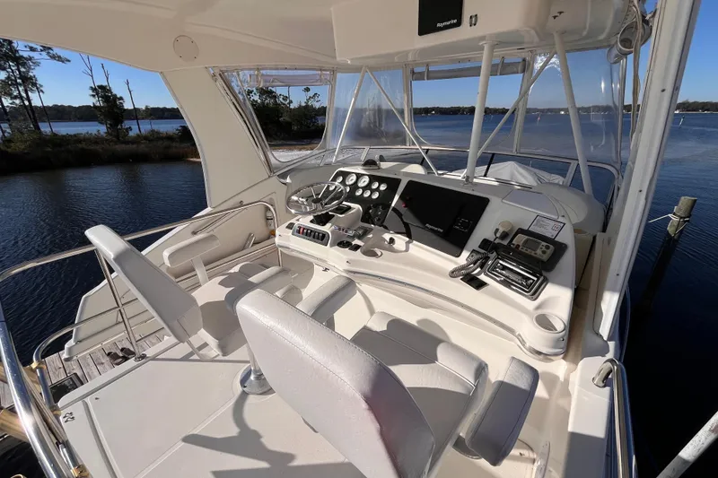 Slide: The Image of 2001 Silverton 42C yacht helm with modern controls, docked by a serene lake. - 30