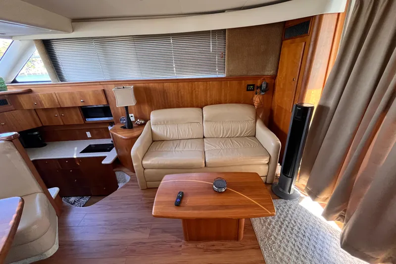 Slide: The Image of Interior of 2001 Silverton 42C yacht with beige sofa, wooden table, and kitchenette. - 46