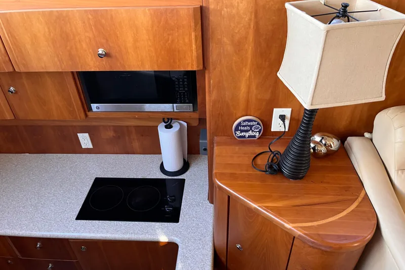 Slide: The Image of 2001 Silverton 42C yacht interior with kitchen and lamp, featuring wooden cabinetry and modern appliances. - 55