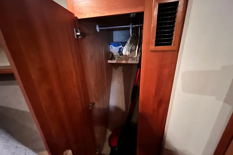 Slide: The Image of Open wooden closet in 2001 Silverton 42C yacht, showing hangers and storage items. - 74