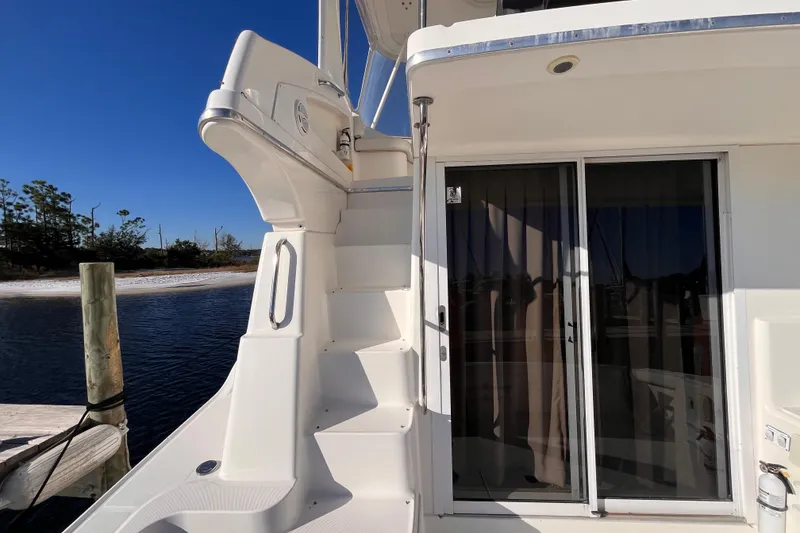 Slide: The Image of 2001 Silverton 42C yacht with stairs and sliding glass door, docked by calm water. - 9
