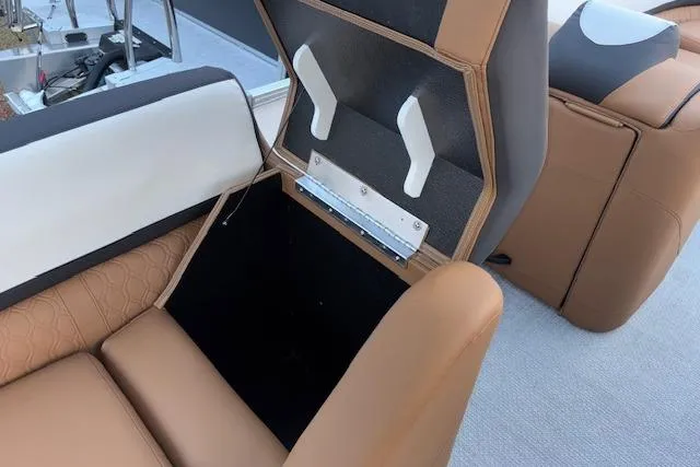 Slide: The Image of 2026 Tahoe Pontoon LTZ 2385 EL Tritoon seat storage compartment, brown and white upholstery. - 33