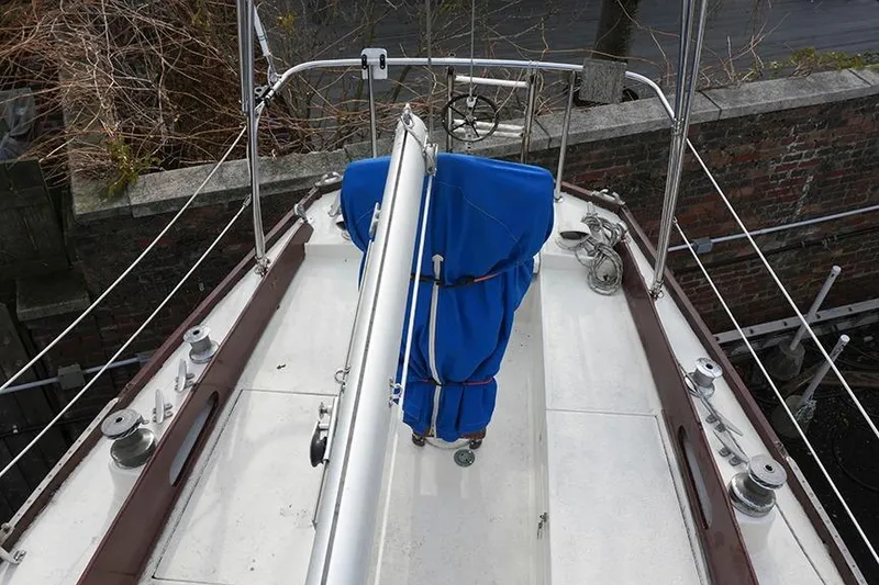 Slide: The Image of 1978 Bristol 29.9 sailboat deck with blue-covered equipment, docked near brick wall. - 12