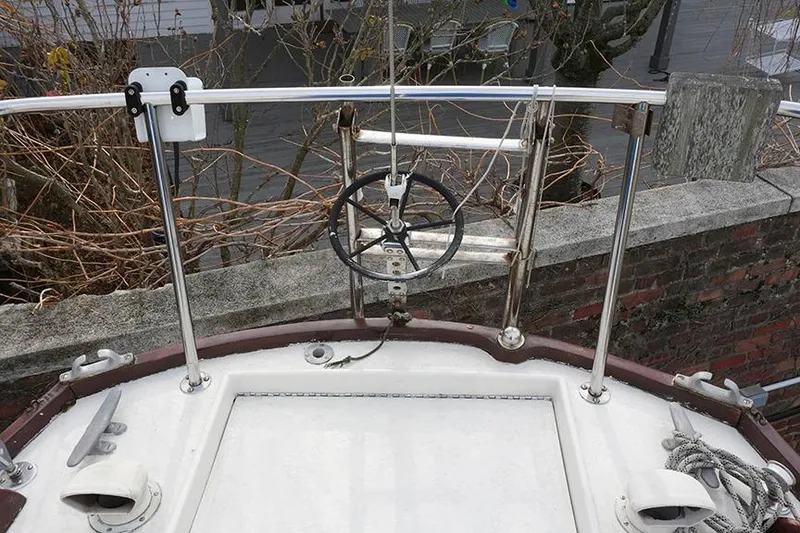 Slide: The Image of 1978 Bristol 29.9 sailboat deck with steering wheel and railing, docked near a brick wall. - 13