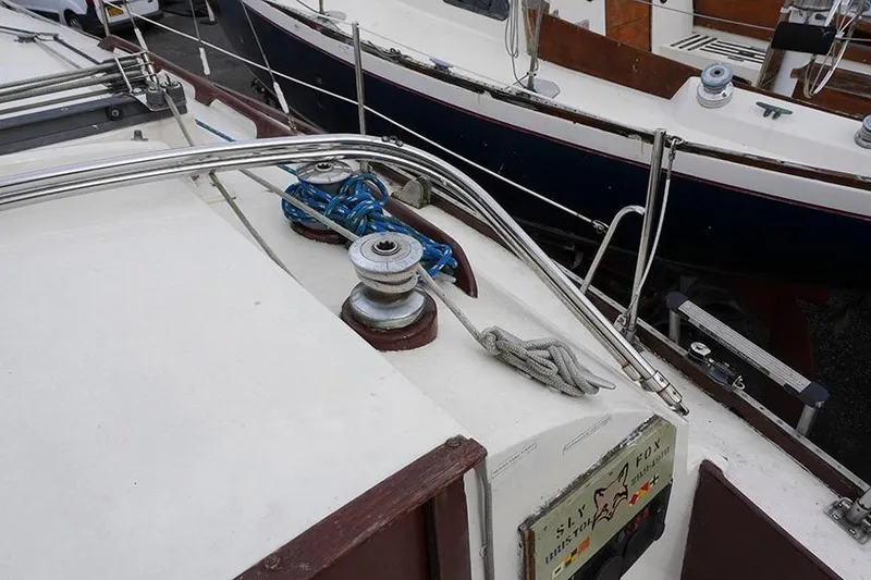 Slide: The Image of 1978 Bristol 29.9 sailboat deck with winches and ropes, docked alongside another boat. - 22