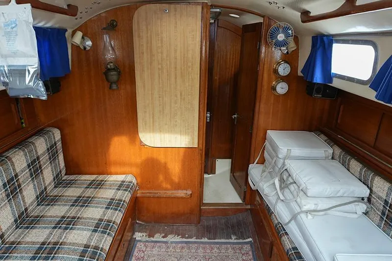 Slide: The Image of 1978 Bristol 29.9 sailboat interior with wood paneling, plaid seating, and nautical decor. - 30