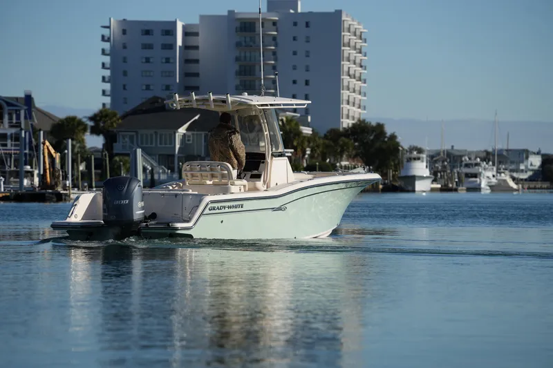 Slide: The Image of 2018 Grady-White Fisherman 236 boat cruising in a marina with buildings in the background. - 21