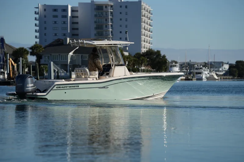 Slide: The Image of 2018 Grady-White Fisherman 236 boat cruising in a calm marina with buildings in the background. - 23