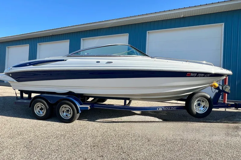 The Image of 2005 Crownline 226 LS boat on trailer, parked near blue building. - 0